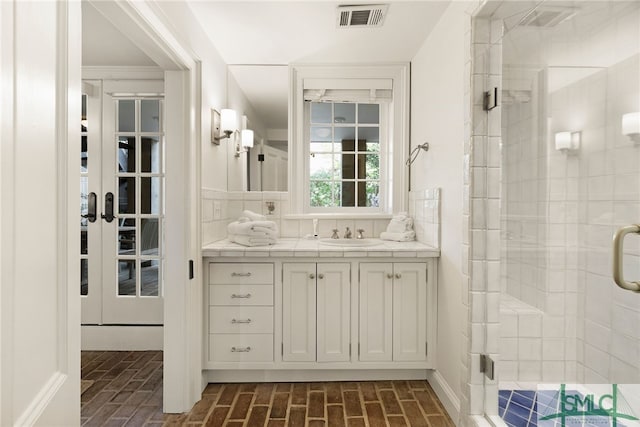 bathroom featuring a shower stall, vanity, visible vents, and brick floor