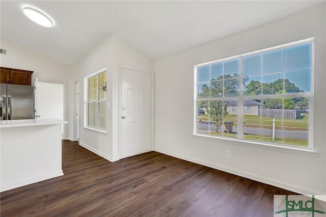unfurnished dining area featuring dark wood finished floors, baseboards, and lofted ceiling