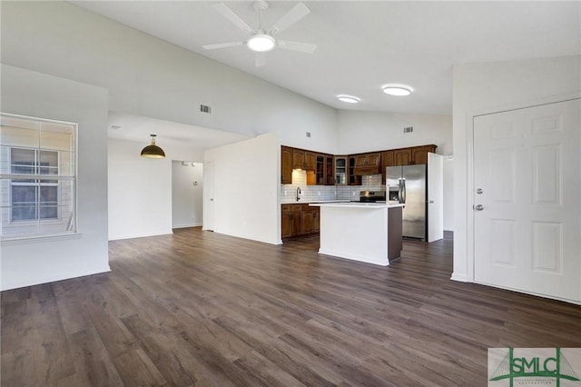 kitchen featuring open floor plan, light countertops, glass insert cabinets, a kitchen island, and appliances with stainless steel finishes
