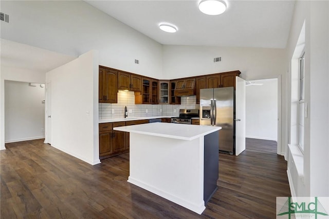kitchen featuring a sink, stainless steel appliances, light countertops, decorative backsplash, and glass insert cabinets