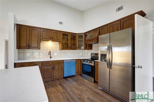kitchen with stainless steel appliances, visible vents, dark wood-type flooring, and a sink