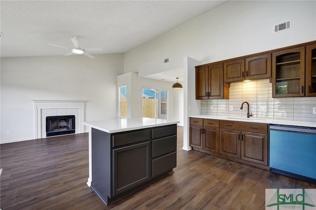 kitchen featuring a sink, dark wood finished floors, a fireplace, dishwasher, and light countertops