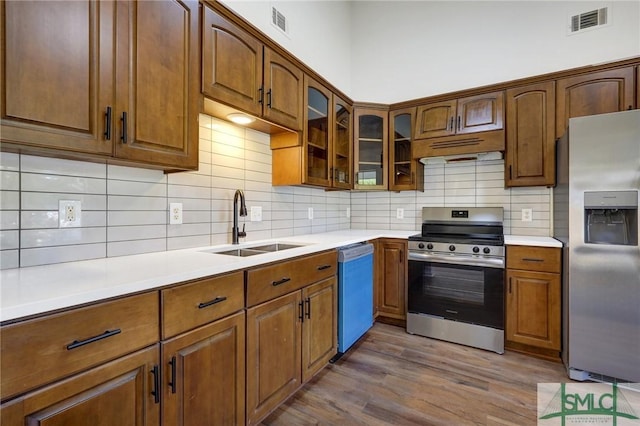 kitchen with a sink, stainless steel appliances, dark wood finished floors, visible vents, and tasteful backsplash