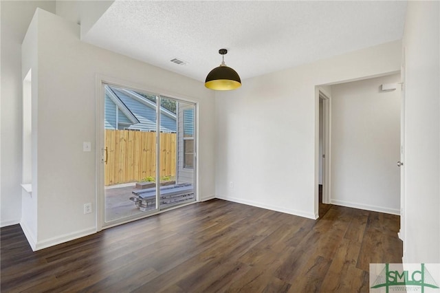 unfurnished room with a textured ceiling, baseboards, visible vents, and wood finished floors