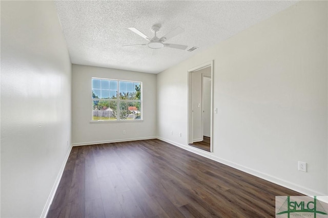 empty room with a textured ceiling, visible vents, dark wood finished floors, a ceiling fan, and baseboards