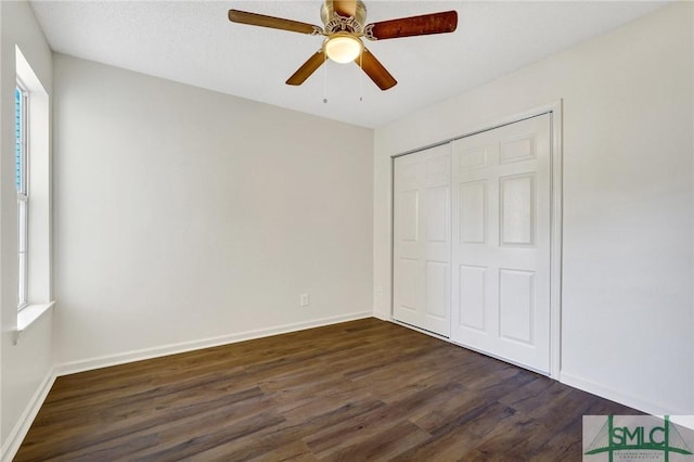 unfurnished bedroom featuring a closet, baseboards, a ceiling fan, and dark wood finished floors