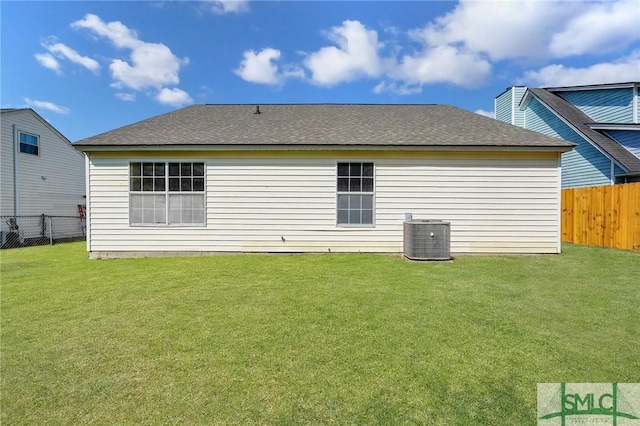back of property featuring a fenced backyard, a shingled roof, cooling unit, and a yard