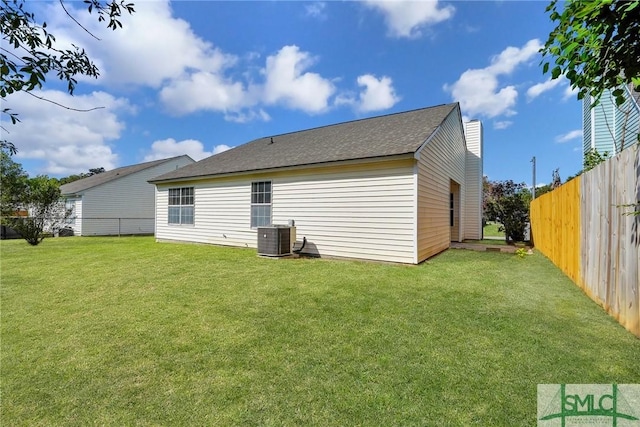rear view of property with a fenced backyard, cooling unit, a chimney, and a lawn