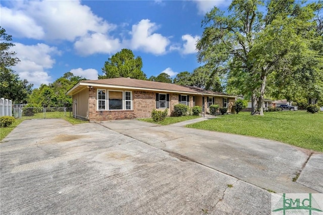 ranch-style house featuring a front lawn, brick siding, driveway, and fence