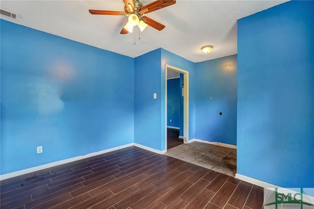 empty room featuring wood finished floors, visible vents, baseboards, and a ceiling fan