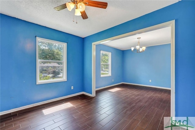 unfurnished room with a textured ceiling, dark wood-type flooring, baseboards, and ceiling fan with notable chandelier