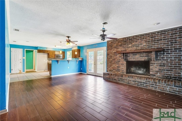 unfurnished living room with a ceiling fan, baseboards, visible vents, and a textured ceiling