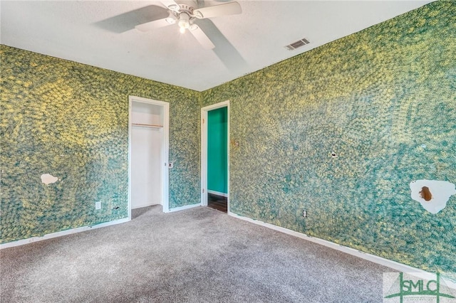 carpeted empty room with ceiling fan and visible vents