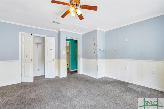 unfurnished bedroom featuring carpet flooring, attic access, wainscoting, and crown molding