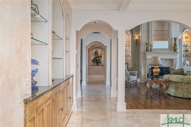 hall with crown molding, built in shelves, and arched walkways