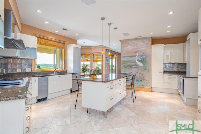 kitchen featuring gas stovetop, a kitchen breakfast bar, visible vents, decorative light fixtures, and decorative backsplash
