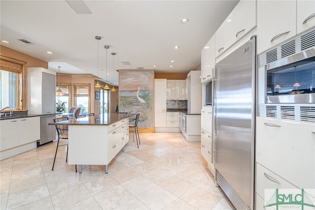 kitchen with built in appliances, a breakfast bar, modern cabinets, and white cabinetry
