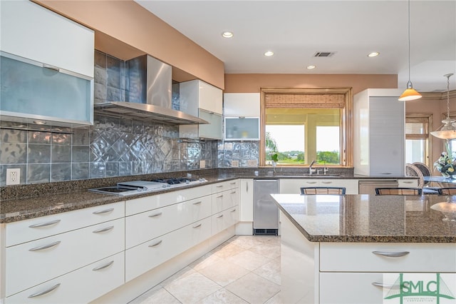kitchen featuring dark stone counters, stovetop, plenty of natural light, and wall chimney exhaust hood