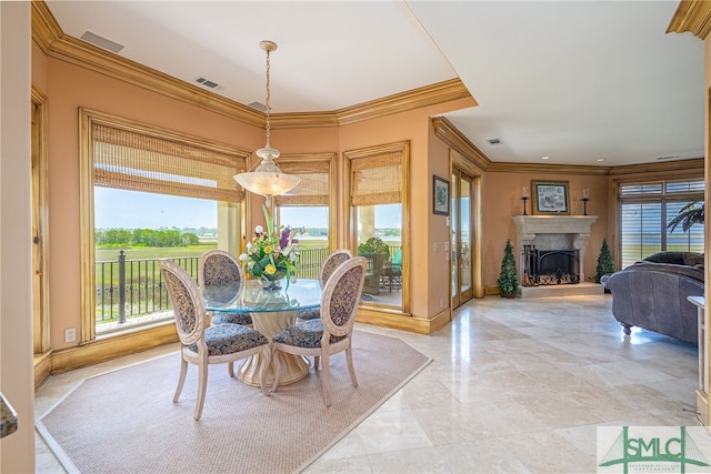 dining area featuring crown molding, a wealth of natural light, a fireplace with raised hearth, and visible vents