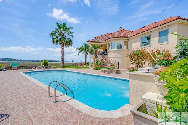 view of swimming pool featuring a patio area, stairway, and a fenced in pool
