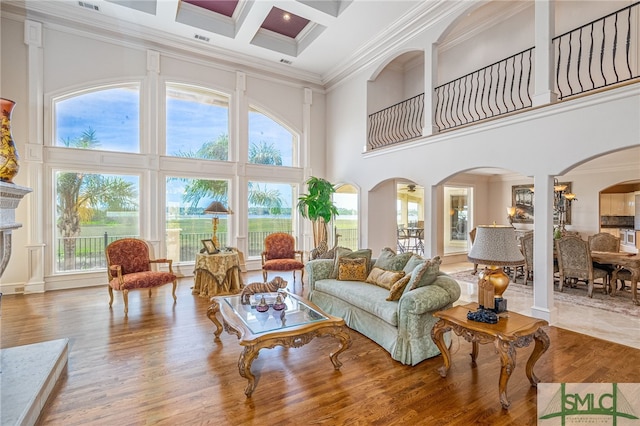 living room featuring wood finished floors, a high ceiling, arched walkways, and decorative columns