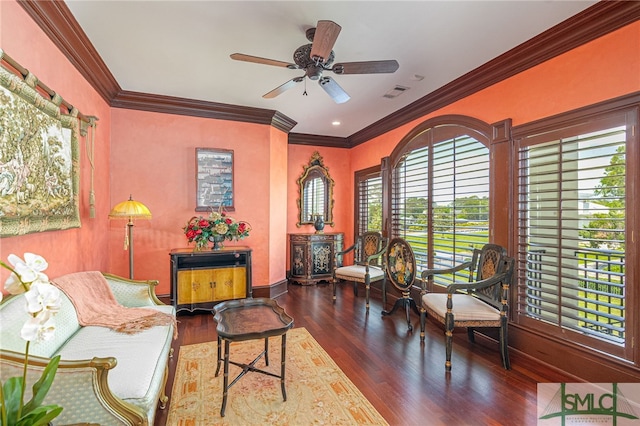 sitting room with ornamental molding, a ceiling fan, visible vents, and wood finished floors