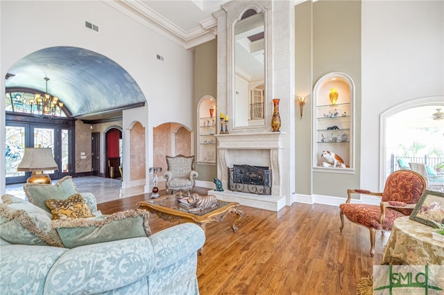 living room featuring arched walkways, a high ceiling, visible vents, and built in features