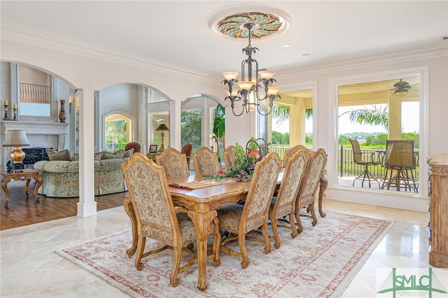 dining space with a notable chandelier, a fireplace, crown molding, and plenty of natural light