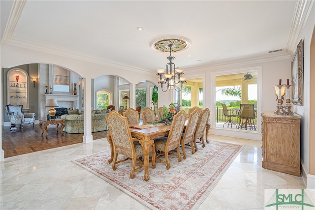 dining space featuring a fireplace, crown molding, visible vents, arched walkways, and a chandelier