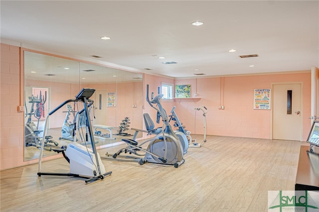 exercise area featuring ornamental molding, recessed lighting, visible vents, and light wood-style floors
