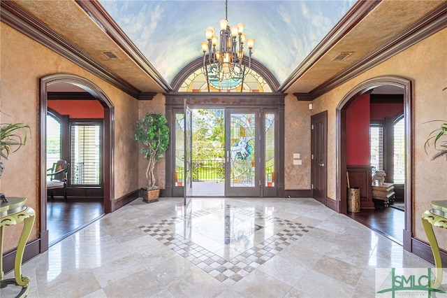 foyer entrance with crown molding, lofted ceiling, arched walkways, and an inviting chandelier