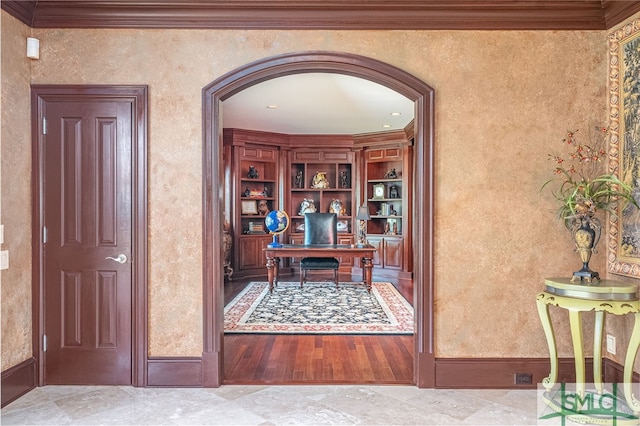 office area with ornamental molding, a textured wall, arched walkways, and baseboards