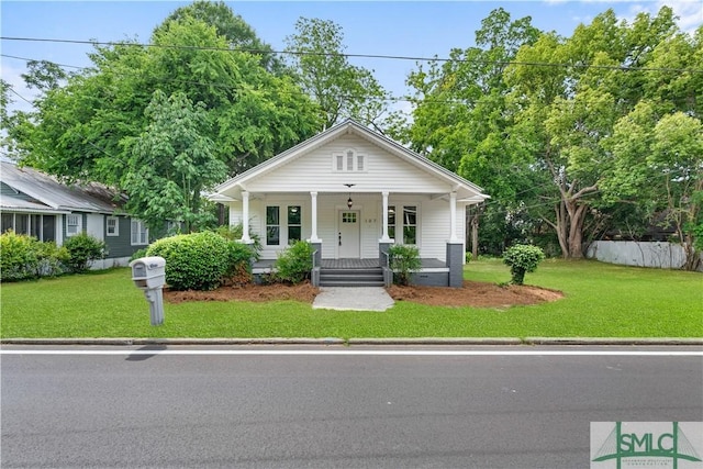 bungalow with a porch, a front lawn, and fence