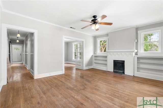 unfurnished living room with ceiling fan, wood-type flooring, a fireplace, and ornamental molding