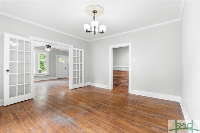 empty room with french doors, ceiling fan with notable chandelier, baseboards, ornamental molding, and hardwood / wood-style flooring