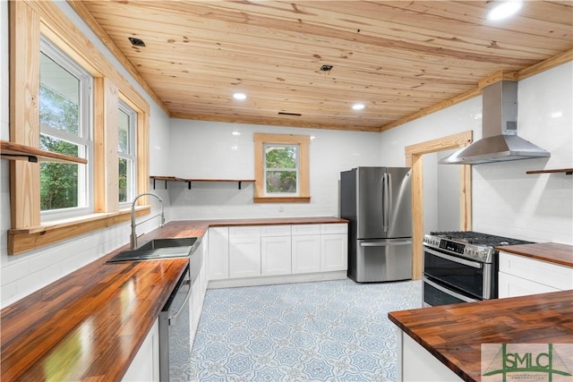 kitchen featuring wall chimney range hood, wooden counters, stainless steel appliances, and wooden ceiling