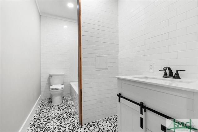 bathroom featuring tile walls, toilet, vanity, tile patterned floors, and baseboards