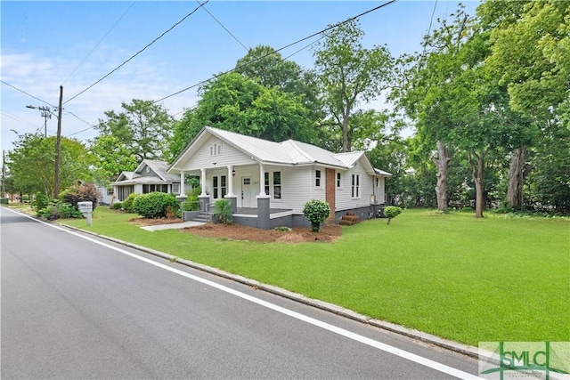view of front of house featuring metal roof, a porch, crawl space, and a front yard