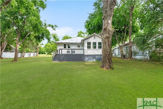 back of house with fence, a lawn, and a deck