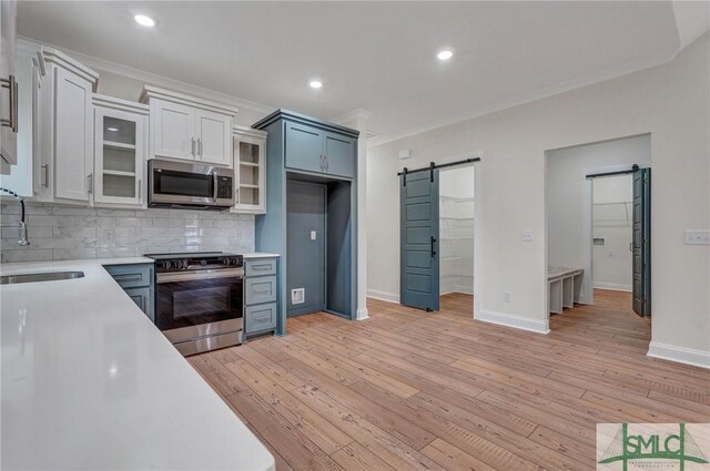 LOT10 Waters Cir, Pembroke, GA 31321 - kitchen featuring a sink, a barn door, backsplash, light countertops, and appliances with stainless steel finishes