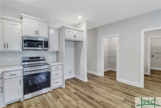 kitchen with stainless steel appliances, light countertops, light wood-type flooring, and baseboards