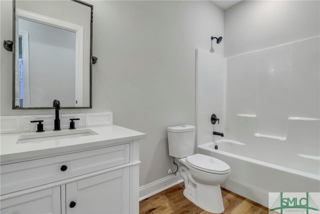 full bathroom featuring toilet, wood finished floors,  shower combination, baseboards, and vanity