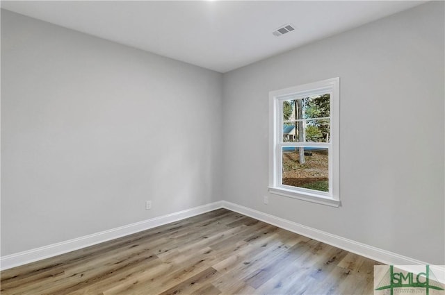 unfurnished room featuring baseboards, visible vents, and wood finished floors