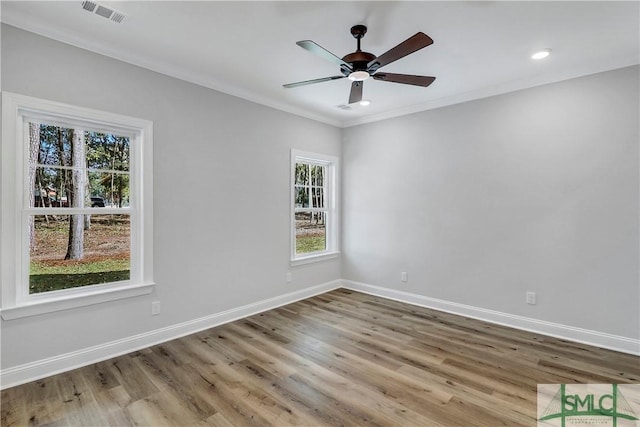 empty room with ceiling fan, ornamental molding, visible vents, and wood finished floors