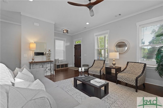 living room with ornamental molding, visible vents, ceiling fan, and wood finished floors