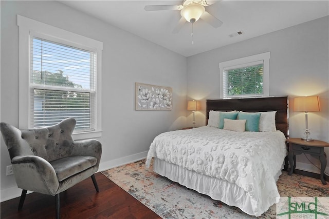 bedroom with baseboards, multiple windows, visible vents, and wood finished floors