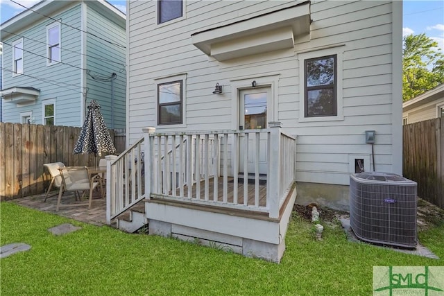 rear view of house with central AC unit, a deck, a yard, and fence