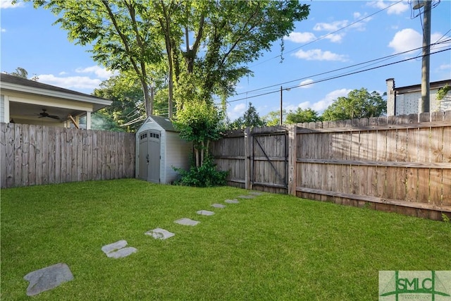 view of yard with a fenced backyard, an outdoor structure, a gate, and a shed