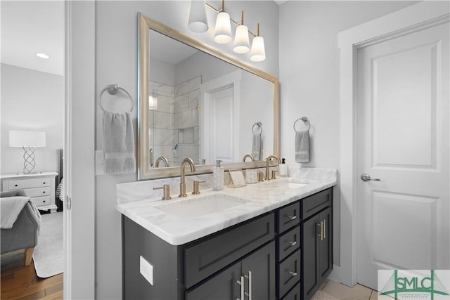 full bathroom with double vanity, a shower, wood finished floors, and a sink