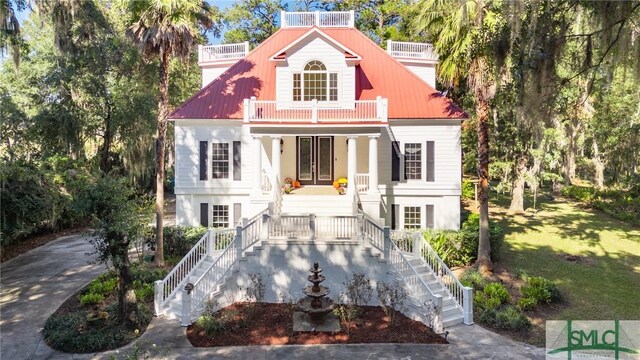 view of front of house with a balcony, french doors, covered porch, stairway, and a front lawn